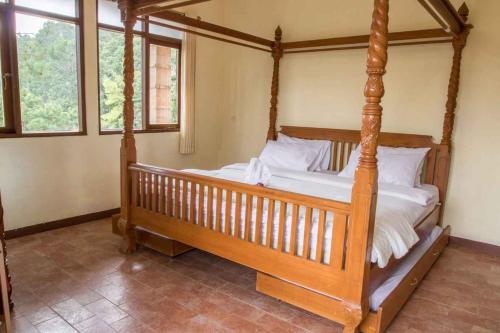 1 dormitorio con cama de madera con dosel y almohadas blancas en Talita Mountain Resort, en Ciseureuh