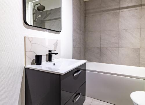 Un baño con lavabo, bañera y espejo. en Le Manège - Troyes hypercentre - 1 min Mairie - Wifi 637 Mbits -, en Troyes