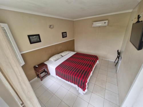 a bedroom with a bed with a red and white blanket at Ecopousada Miriti in Belém