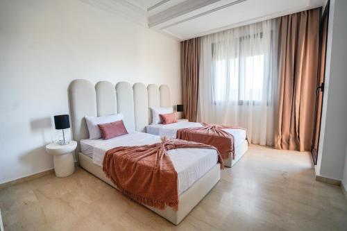 une chambre d'hôtel avec deux lits et une fenêtre dans l'établissement œil de la vallée, à Marrakech
