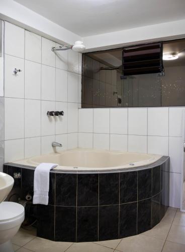 a bathroom with a tub and a toilet and a mirror at Los Chullos in Cusco