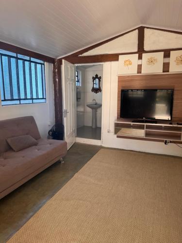 a living room with a couch and a flat screen tv at Cute Rustic Cottage by the River in Caximba