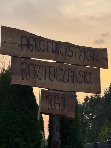 a wooden street sign with writing on it at Roztoczański Raj in Rogóźno