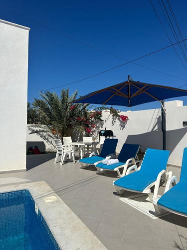 a group of blue lounge chairs and a swimming pool at Villa Aline Lagune Djerba in Midoun