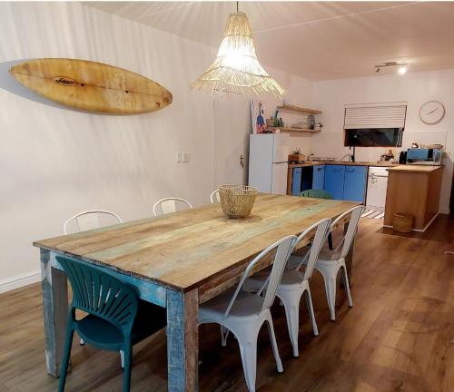 a dining room table with chairs and a surfboard on the wall at 8 Eden Villa in Yzerfontein