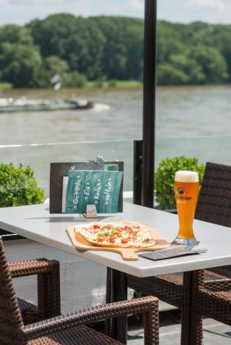 a table with a pizza and a glass of beer at Rheinterrassen Hotel Café Restaurant in Widdig