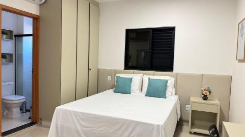 Un dormitorio con una cama blanca con almohadas azules. en 107-4 · Suíte Aconchego Blue prox. UniEvangélica, en Anápolis