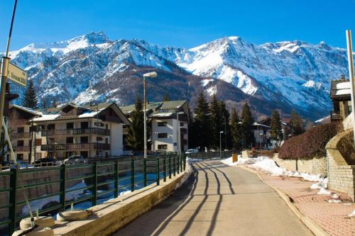 a street in a town with snow capped mountains at Bramé La Fam 32 few steps from skiing - Happy Rentals in Bardonecchia