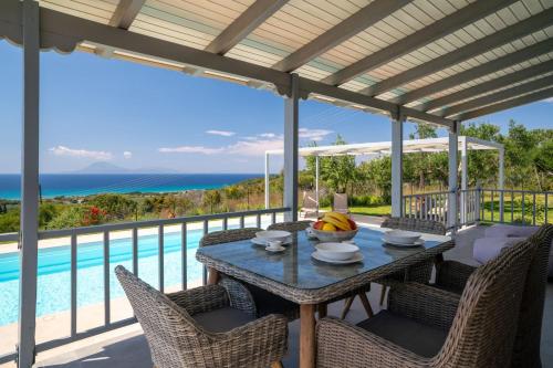 a patio with a table and chairs and a pool at Villa Filokalia With Exceptional View - Happy Rentals in Kastro Kyllini