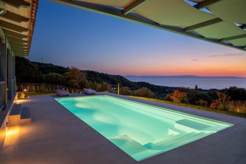 a swimming pool in a house with a sunset at Villa Filokalia With Exceptional View - Happy Rentals in Kastro Kyllini