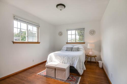 a white bedroom with a bed and two windows at Central Menomonee Falls Condo WFH Friendly in Menomonee Falls