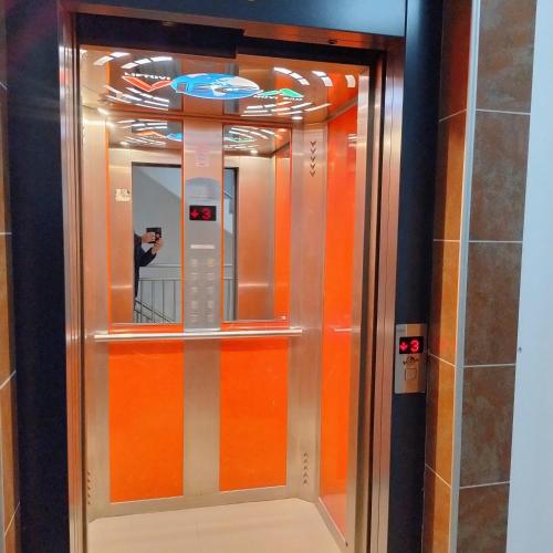 a mirror in a elevator with a person taking a picture at Knez in Požarevac