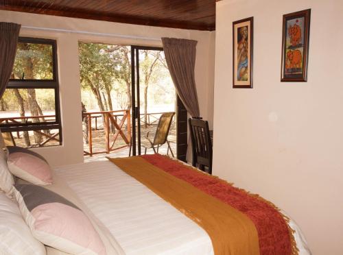 a bedroom with a bed and a large window at Kruger River Holiday Home in Marloth Park
