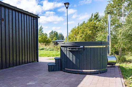 a black trash can sitting next to a fence at Lielpīles in Radziņciems