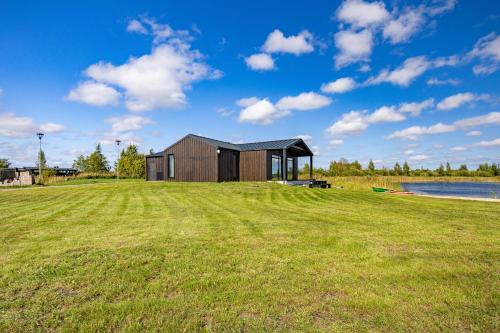 a house on a grassy field with a building at Lielpīles in Radziņciems