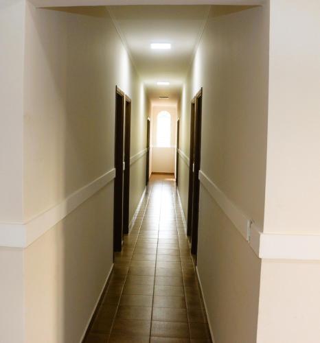an empty hallway with dark doors and tile floors at Hotel Nova Sorocabana in Brodósqui