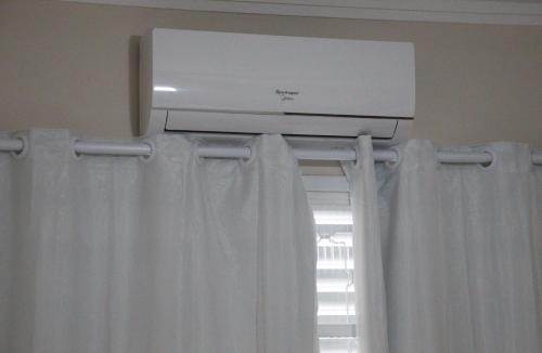 a air conditioner above a window with white curtains at Hotel Nova Sorocabana in Brodósqui