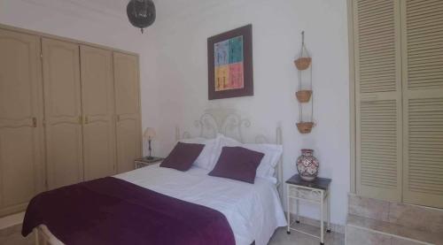 - une chambre dotée d'un lit avec des draps violets et blancs dans l'établissement Riad Diaz Taghazout, à Ikouzza