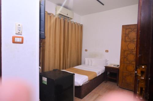 a small bedroom with a bed and a wooden door at New Alhussien Hotel in Asyut