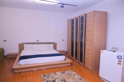 a bedroom with a bed and a wooden cabinet at New Alhussien Hotel in Asyut