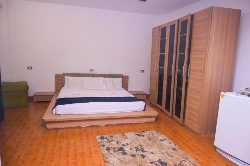 a bedroom with a bed and a wooden cabinet at New Alhussien Hotel in Asyut