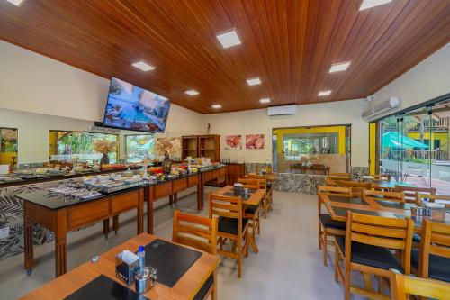 a restaurant with wooden tables and chairs and a flat screen tv at Pousada Tropicarim in Itacimirim