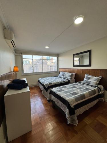two beds in a room with two windows at Departamentos Familiares Santiago de Chile in Santiago