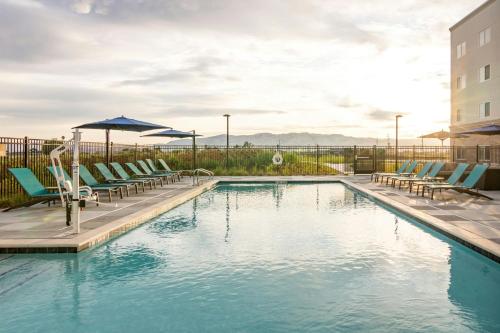a pool with chairs and umbrellas next to a building at Fairfield Inn & Suites by Marriott San Jose North/Silicon Valley in San Jose