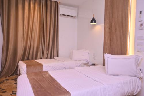 a hotel room with two beds and a window at New Alhussien Hotel in Asyut