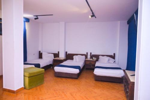 a room with three beds in a room at New Alhussien Hotel in Asyut