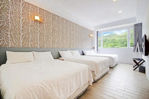 two beds in a room with a wall with trees at House16 in Green Island