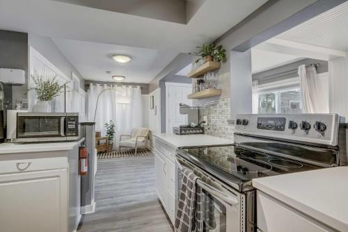 a kitchen with white cabinets and a stove top oven at Euro Cottage - Downtown Convenience BBQ Fire Pit in Colorado Springs