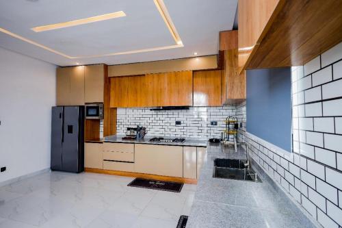 Una cocina con gabinetes de madera y un refrigerador negro. en 4 bedroom penthouse, en Lekki
