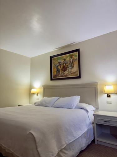 a bedroom with a white bed and a painting on the wall at Hotel La Mansión in Río Bravo