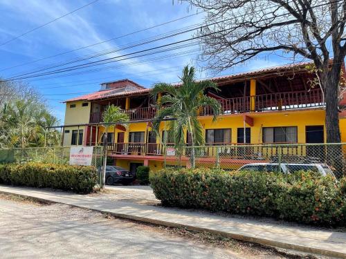 a yellow building with balconies on a street at Hotel Georgi, Guanacaste CR in Guanacaste