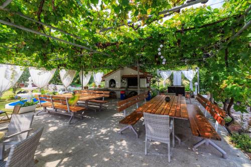a group of wooden tables and chairs under a tree at Apartments Mig in Supetarska Draga