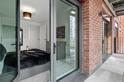 リバプールにあるCentral Liverpool Luxury 2BR w Balcony & 2 Bathsのベッド1台とガラスドアが備わる客室です。