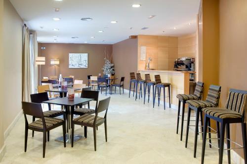 a dining room with tables and chairs and a kitchen at Gran Hotel Suances in Suances