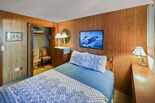 1 dormitorio con 1 cama azul y paredes de madera en Ocean's Edge Escape, en Twin Rocks