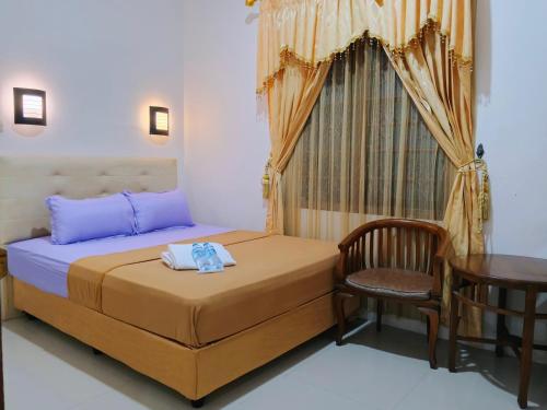 a bedroom with a bed and a chair and a table at Among Rogo Syariah in Yogyakarta