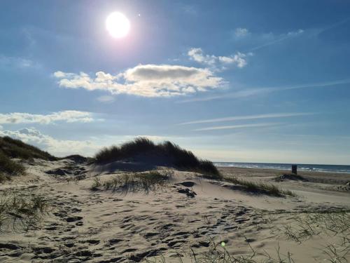 a sandy beach with the sun in the sky at 6 person holiday home in Pandrup-By Traum in Pandrup
