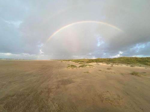 a rainbow in the sky over a sandy beach at 6 person holiday home in Pandrup-By Traum in Pandrup