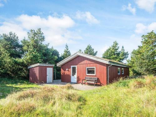 a red tiny house with a deck in a field at 6 person holiday home in Rømø-By Traum in Bolilmark