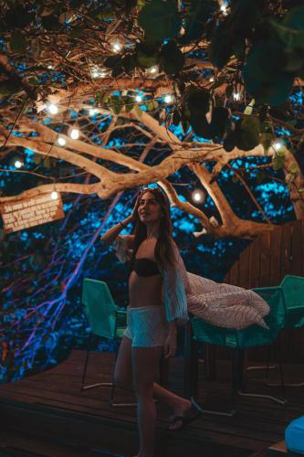 a woman in a bikini standing in front of a tree at Khaban Bacalar Hotel Boutique in Bacalar