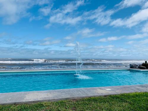 a fountain in the middle of a swimming pool near the ocean at Hotel La Roca Costa Esmeralda in Monte Gordo