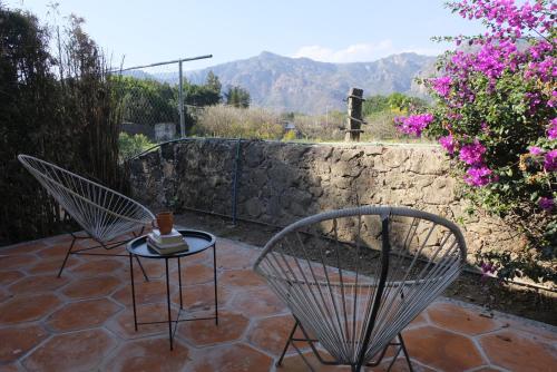 a patio with two chairs and a table and flowers at Villas Mexiko in Tepoztlán