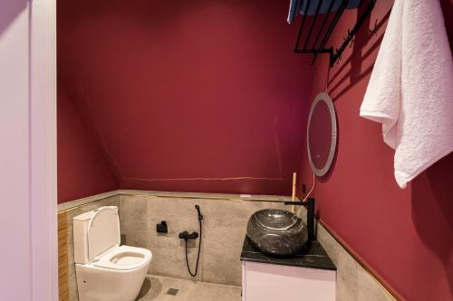 a bathroom with a toilet and red walls at AFrame Villa Riverside GABALA in Gabala