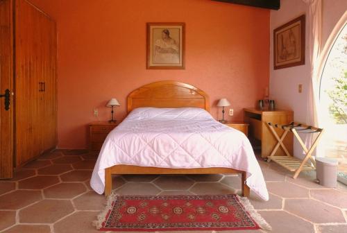 a bedroom with a bed with an orange wall at Villas Mexiko in Tepoztlán