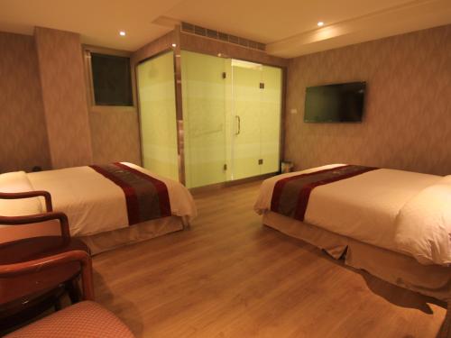 a hotel room with two beds and a tv at Wonderful Hall Hotel in Xinzhuang