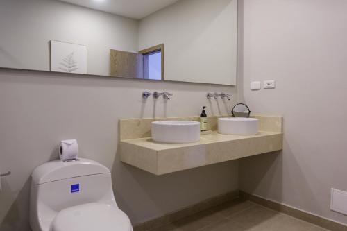 a bathroom with a toilet and two sinks and a mirror at Hotel Santa Cecilia B&B in Cartagena de Indias